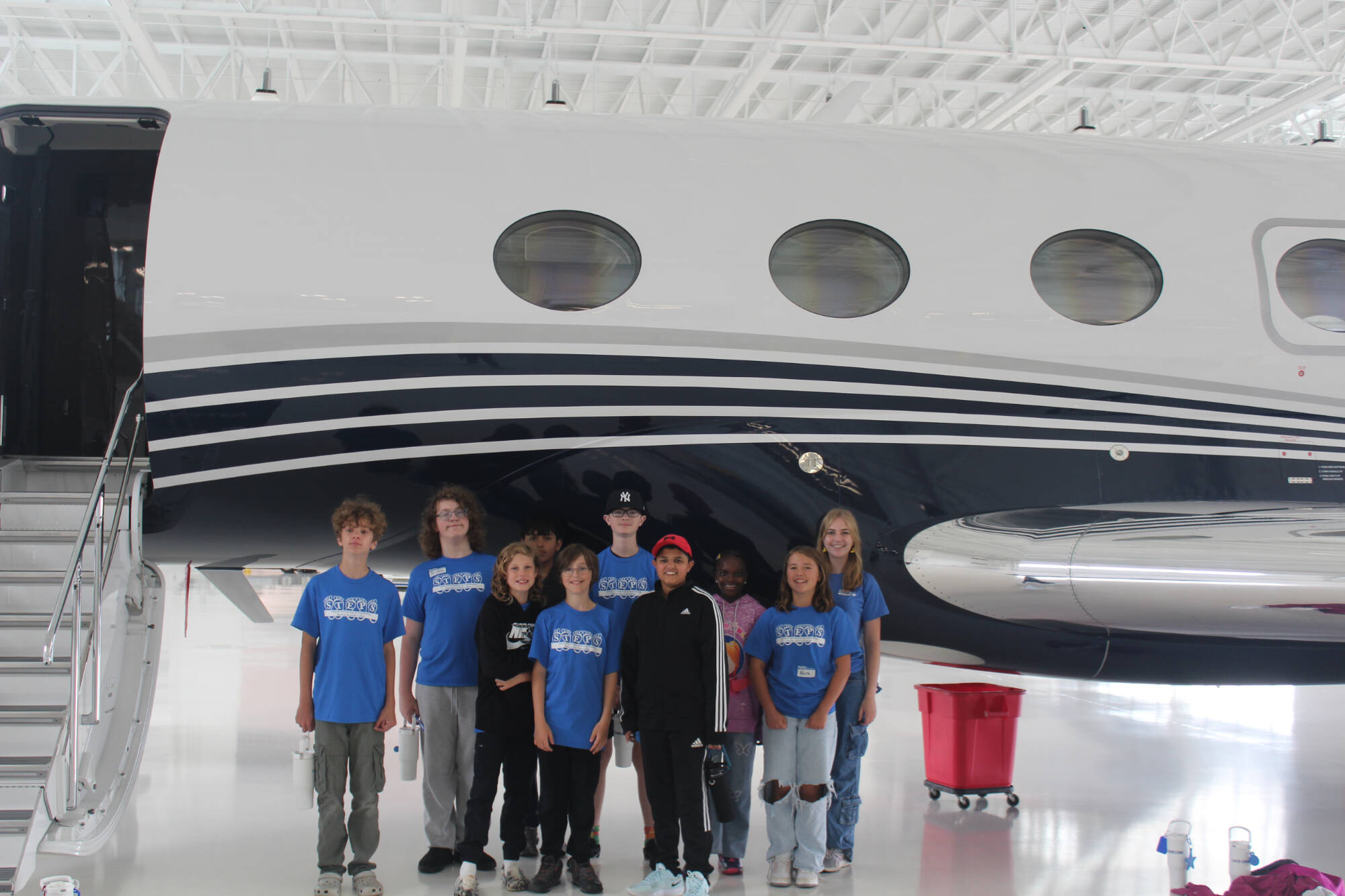 A group of STEPS students stand in front of airplane